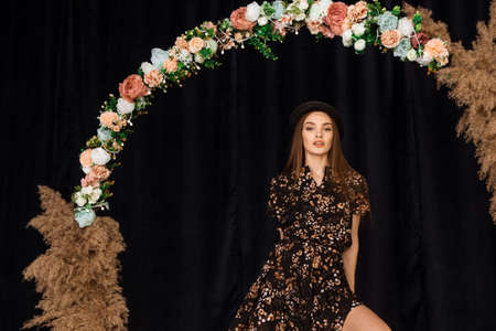 Beautiful woman posing at circle of deadwood in dress with flower print in studioの写真素材