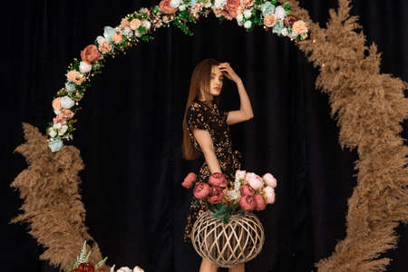 Beautiful woman posing at circle of deadwood in dress with flower print in studioの写真素材