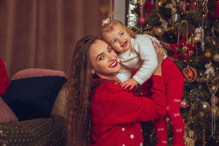 Happy young mom with little baby girl celebrate Christmas and New yearの写真素材