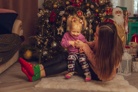 funny mother with her little baby girl sits on the couch at home and screamsの写真素材