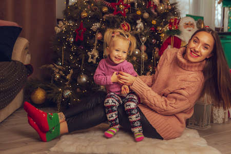 portrait of cute mother and daughter at the christmas treeの写真素材