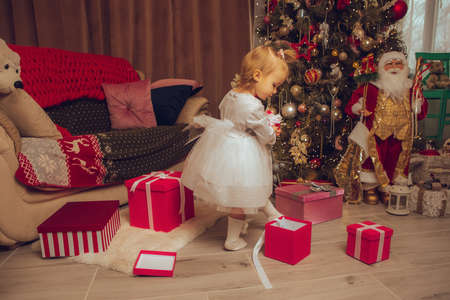 little happy baby girl with a xmas tree from behind at homeの写真素材