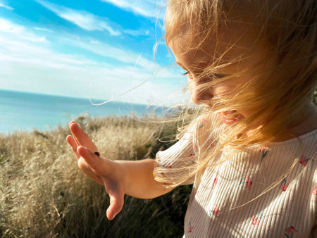 happy girl plays with ladybug on her finger and smilesの写真素材