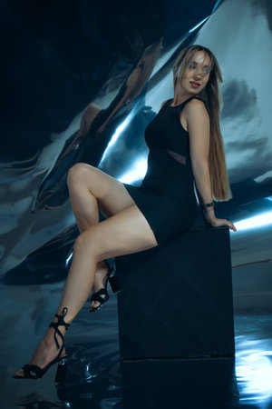 Sexy fashionable lady in black dress posing in studio on dark foil backgroundの写真素材
