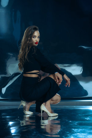 Sexy fashionable lady in black dress posing in studio on dark foil backgroundの写真素材