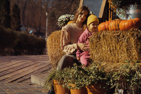 pretty mother and her little daughter at autumn time outdoorsの写真素材