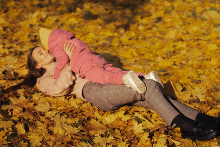 happy mother and her little daughter in autumn forest having funの写真素材