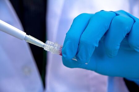Pipette with drop of liquid in a science research lab 