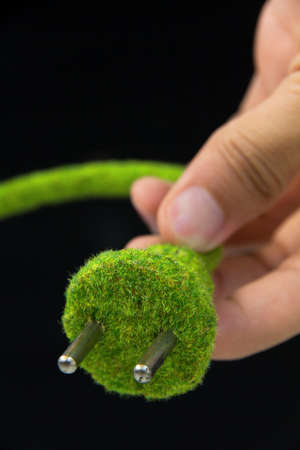 hand holding green electric plugの写真素材