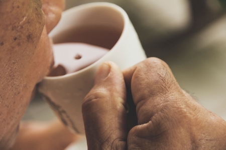 a hand ilfts a cup of teaの写真素材