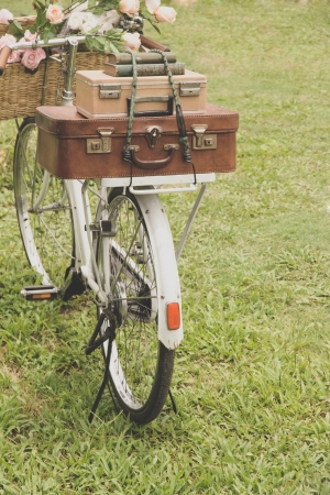 Vintage bicycle on the field with a basket of flowers and bagの写真素材