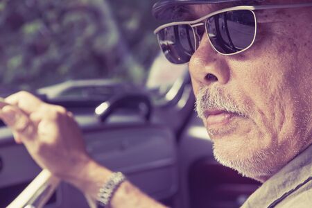 Older man with glasses driving a carの写真素材