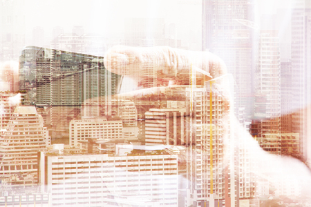 Double exposure of man using smart phone and cityscape backgroundの写真素材