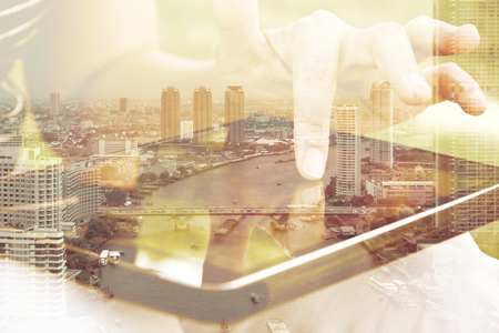 Using digital tablet double exposure and and cityscape background. Business  technology concept.の写真素材