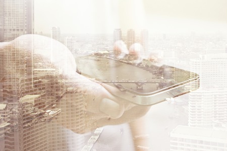 communication technology concept.Double exposure image of people with smart phone and cityscape backgroundの写真素材
