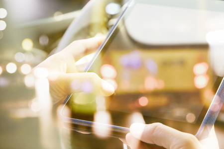 image of people sitting in the car using digital tablet double exposure and blurred view of car on...