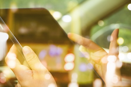 image of people sitting in the car using digital tablet double exposure and blurred view of car on...