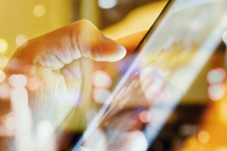 close up of Male fingers touching tablet screen double exposure and blurred view of car on street at...