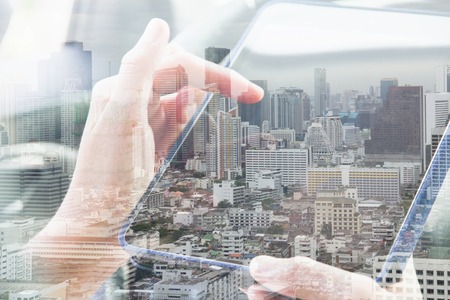 Using digital tablet double exposure and and cityscape background.Communication technologyの写真素材