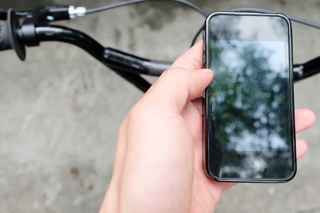 Close up image of man hand with bicycle texting on mobile phoneの写真素材