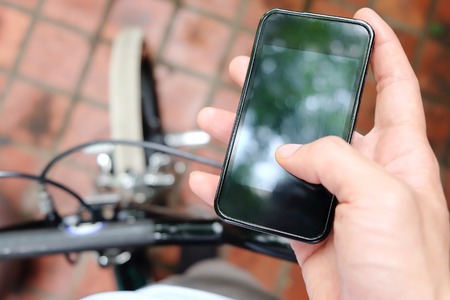 image of a biker texting on a smart phoneの写真素材