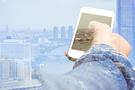 Double exposure image of smart phone with cityscape background,Communication technology conceptの写真素材