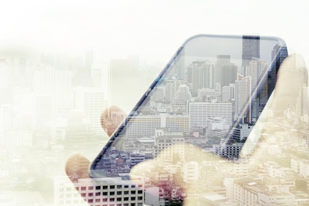 Double exposure image of smart phone with cityscape background,Communication technology conceptの写真素材