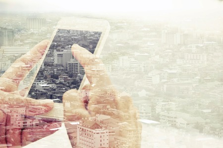 Double exposure of man using smart phone and cityscape background ,Business technology concept.の写真素材