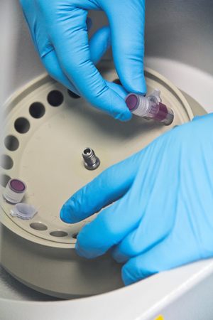 Research scientist putting test tube into real-time pcr machineの写真素材