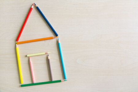 Crayons arranged as a symbol of the house on a wooden floor, house conceptの写真素材