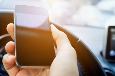 Image of male hand holding a phone whilst inside a carの写真素材