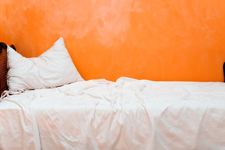 White sofa in front of orange wallの写真素材