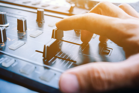 Close up image of DJ turntable console mixer controlling