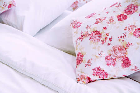 Bright bedroom interior with flower pattern pillows on bedの写真素材
