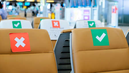 Social distancing, Rows of empty chairs in an airport's departure area marked with symbols regarding social distancing protocol to prevent the spreading of novel corona virus, COVID-19 in Thailandのeditorial素材