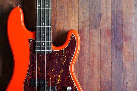 orange electric bass guitar on wood background with copy spaceの写真素材