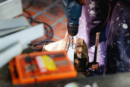 Worker using electric drill to cut metal on industrial construction site.の写真素材