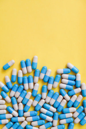 Blue and white pills on yellow background. Top view with copy spaceの写真素材