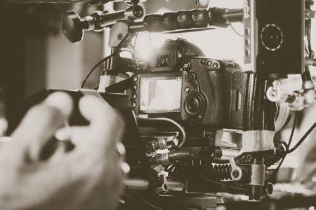 Closeup of professional videographer working on camera. Filtered image processed vintage effect.