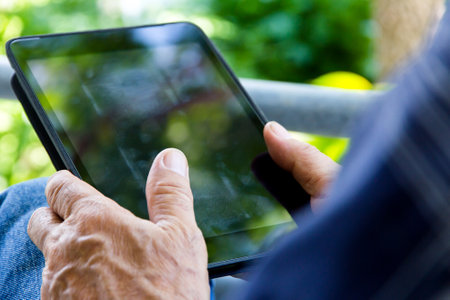 Elderly woman using tablet pc in the garden, close upの写真素材