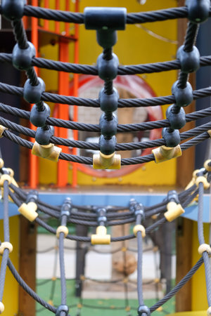 Close-up view of colorful playground rope bridge for children's outdoor recreational equipment in a...