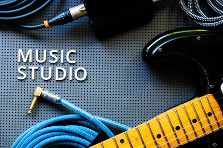 Electric guitar, Instuments and cable on a gray background with the word Music Studio. Music concept