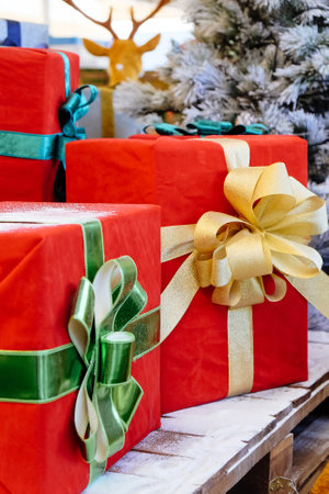 Christmas presents in red and green boxes with ribbons on wooden shelfの写真素材
