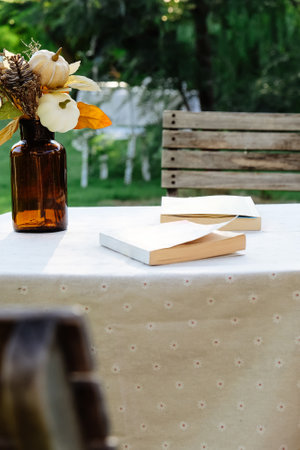 Wooden table with a book and a glass vase with flowersの写真素材