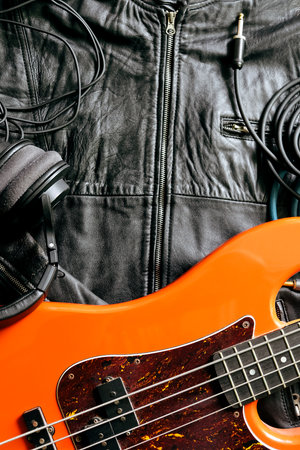 orange electric guitar with headphones on a black leather jacket, close up