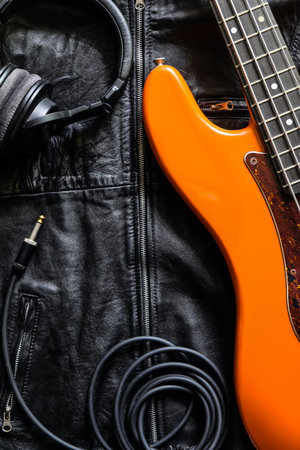 Electric guitar, headphones and leather jacket on a black background. Top view.