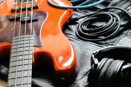 orange electric guitar and headphones on a black leather case close-up