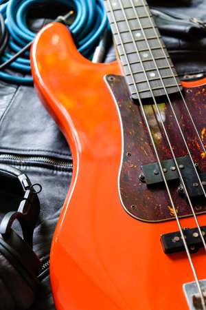 Electric guitar with headphones on the background of a black leather jacket.