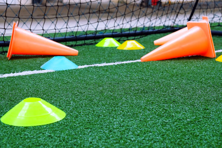 Soccer cones on green artificial turf, sport background.