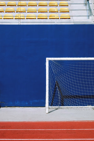 Soccer goal on the blue wall of a sports arena with bleachersの写真素材